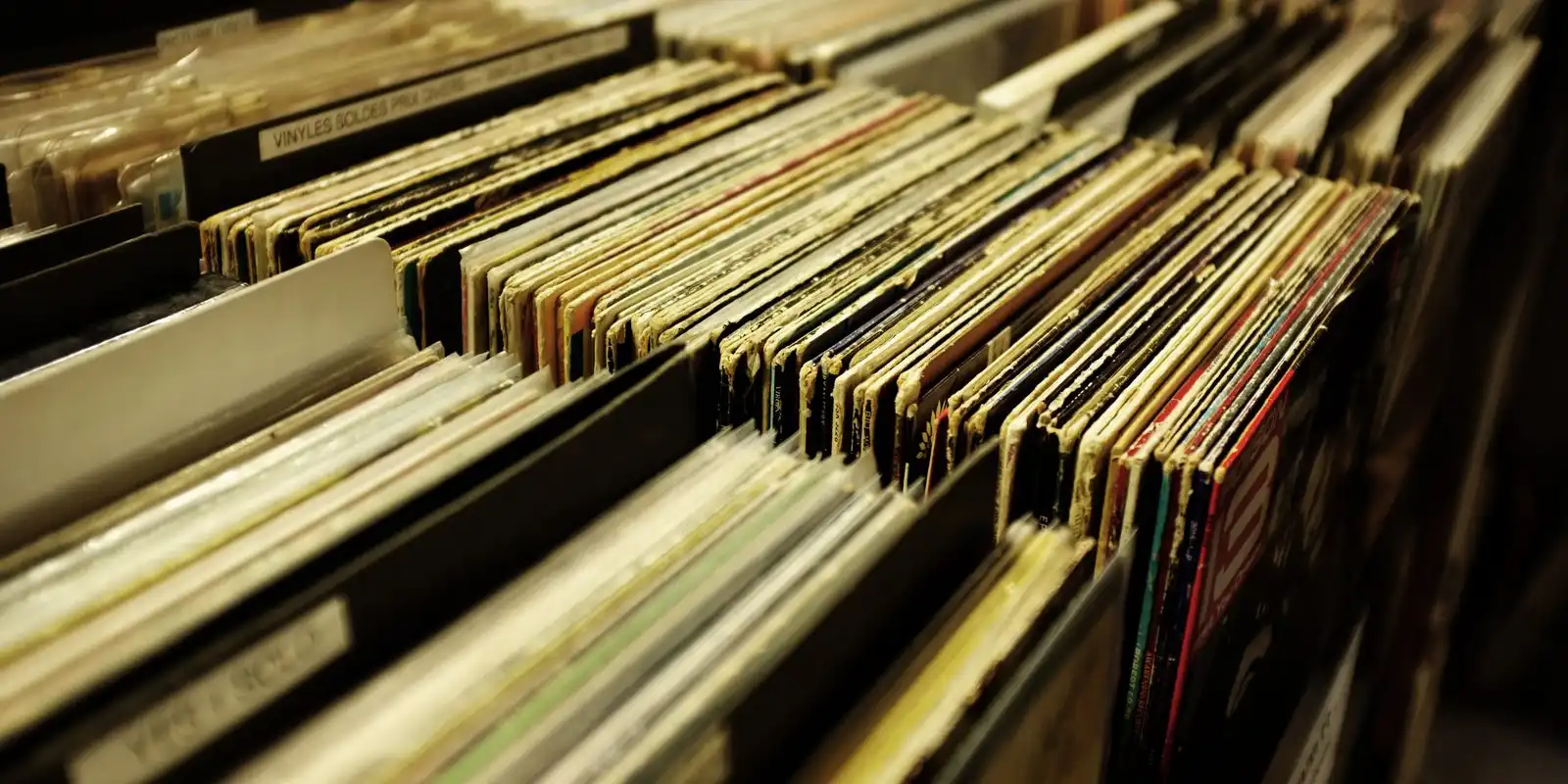 Rows of second-hand records packed into wooden bins in a shop