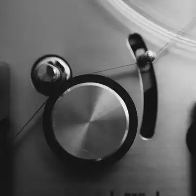 Black-and-white close-up of a reel-to-reel tape machine's capstan and tape path