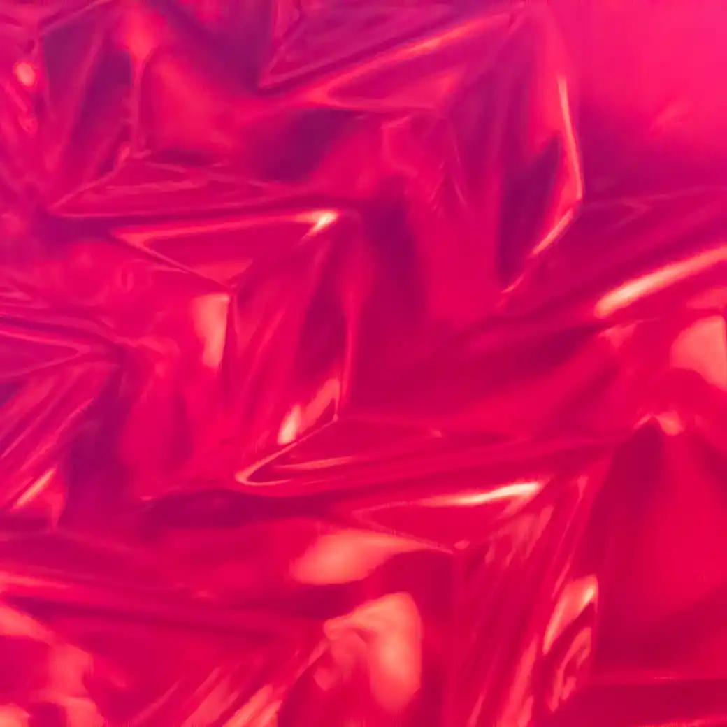 Crumpled magenta and red foil catching light in sharp folds