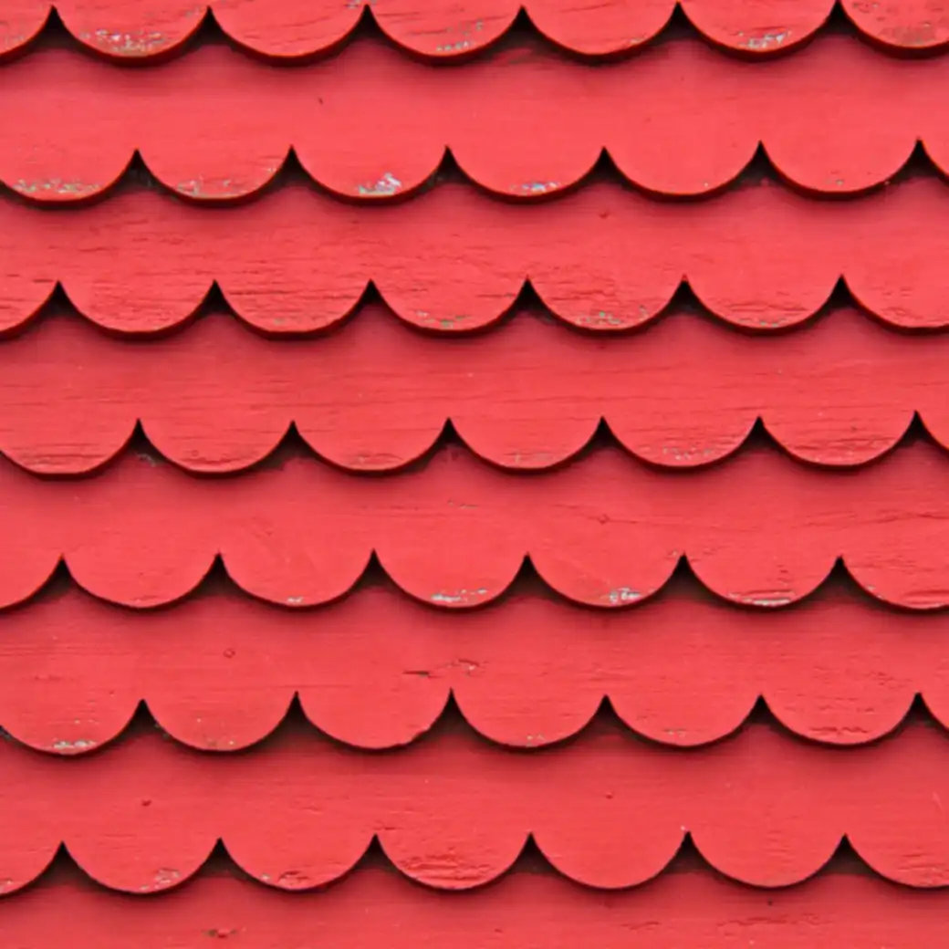 Rows of scalloped coral-red wooden roof shingles