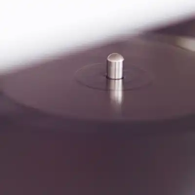 The spindle of a turntable platter in soft focus, in deep plum light